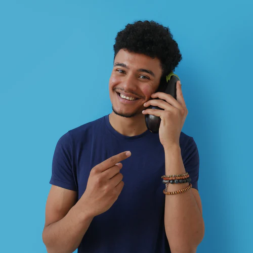 Young man with curly hair smiling and holding a phone to his ear against a background of rubies.