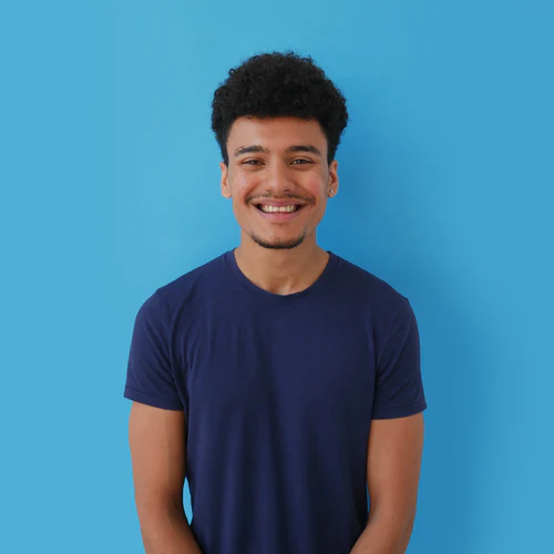 Young man with curly hair smiling in a blue t-shirt against a background of 