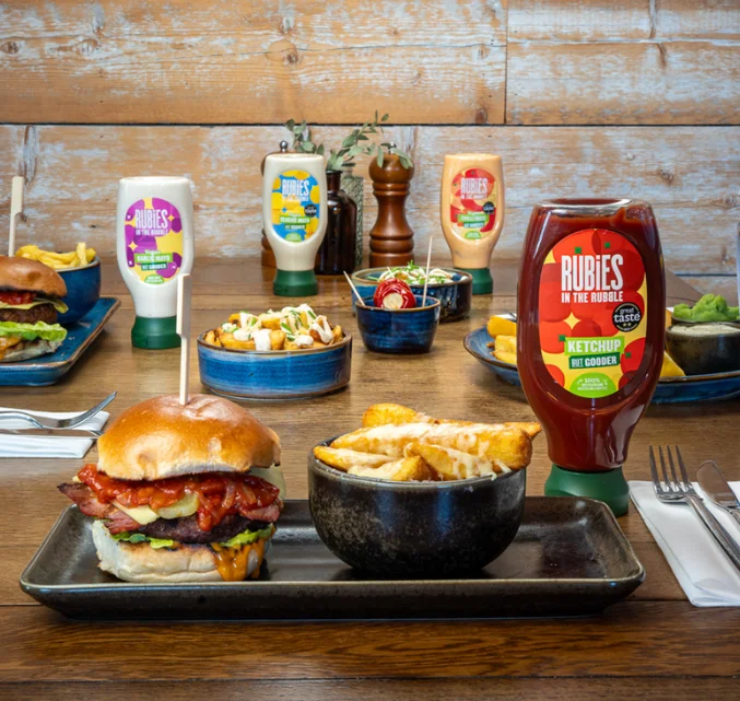 Rubies in the Rubble ketchup, classic mayo, garlic mayo and chilli mayo placed on a table surrounded by burgers and chips